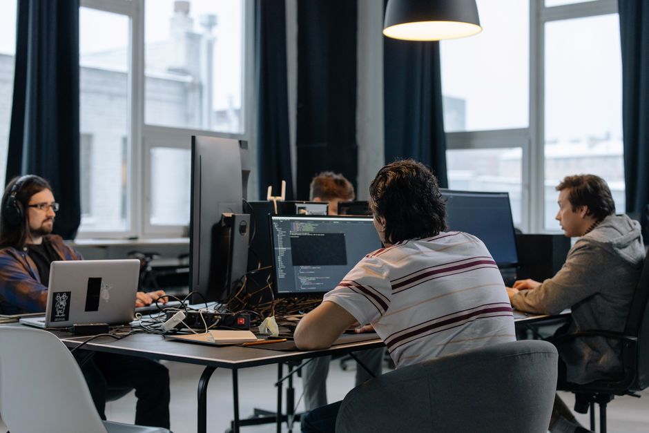 Tim developera koji zajedno rade na računalima u modernom tech uredu